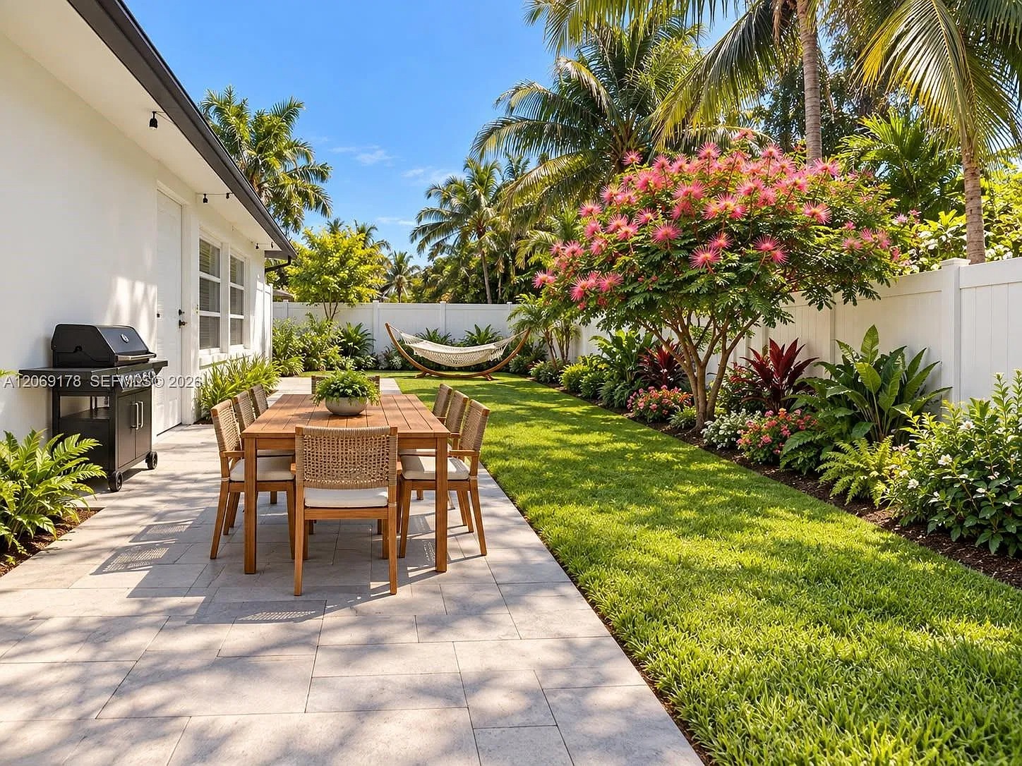 Private tropical backyard with outdoor dining, grill, and hammock