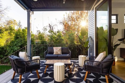 Stylish Covered Patio Retreat! ☀️ Enjoy sun-drenched private seating with a comfy black modern sofa and chairs set on a chic black & white geometric rug. Surrounded by lush greenery, this is the perfect spot for morning coffee!