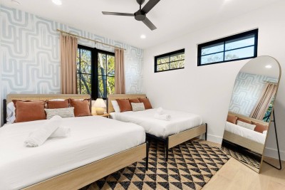 This fun, vibrant room features two comfortable Queen beds with patterned pillows. Enjoy the designer wallpaper accent wall and large full-length mirror. A great space for four guests to share! Unique and thoughtfully designed.