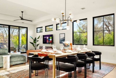 Sun-Drenched Dining & Entertaining! ️ This stunning space features a long wooden dining table beneath a modern chandelier. Enjoy incredible natural light and views through oversized black-framed windows and a sliding glass door.