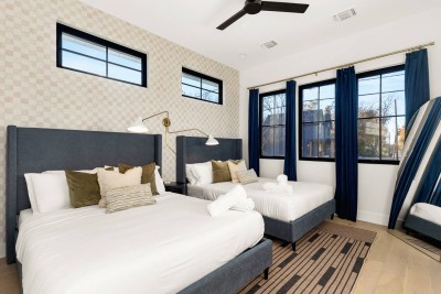 Spacious Bedroom! ️️ Ideal for friends or families, this stylish room features two comfortable Queen beds with tall upholstered headboards. Enjoy the bold accent wall, striking blue curtains, and modern lighting. A ceiling fan and unique decor!