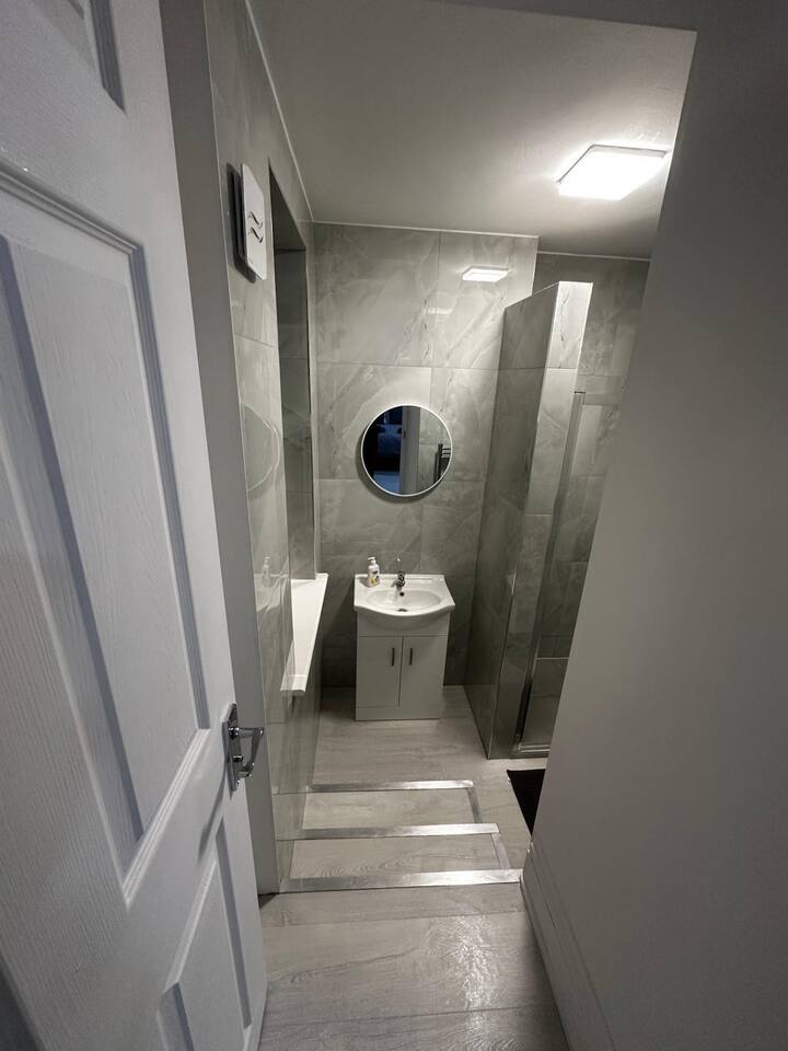 Sleek marble-tiled bathroom in Shepherd’s Bush with a walk-in shower, modern vanity and soft wood flooring. Just minutes from Hammersmith, it’s compact, elegant and thoughtfully designed for refreshing in style.