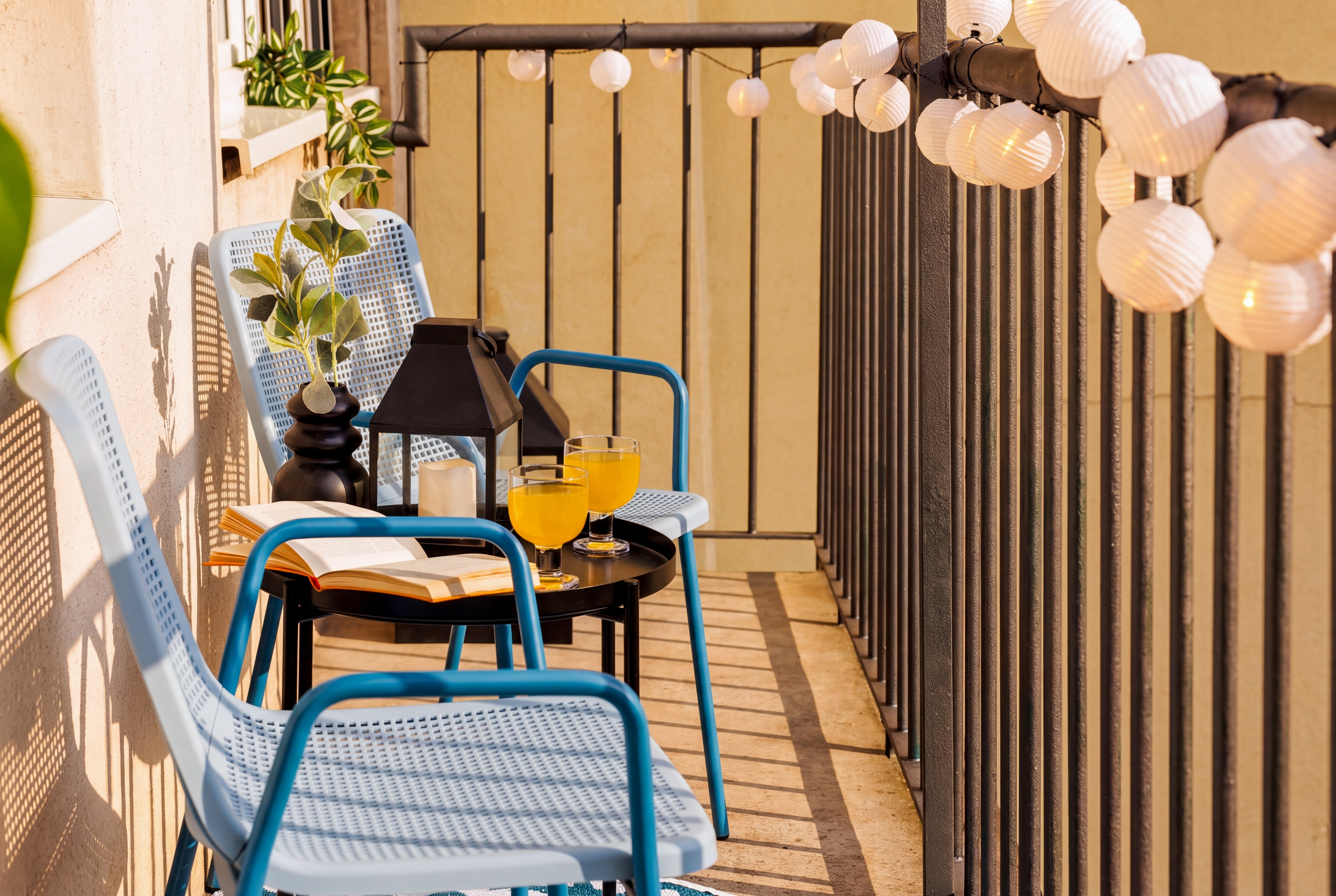 Sunny private balcony with cozy seating, string lights, and relaxing vibes
