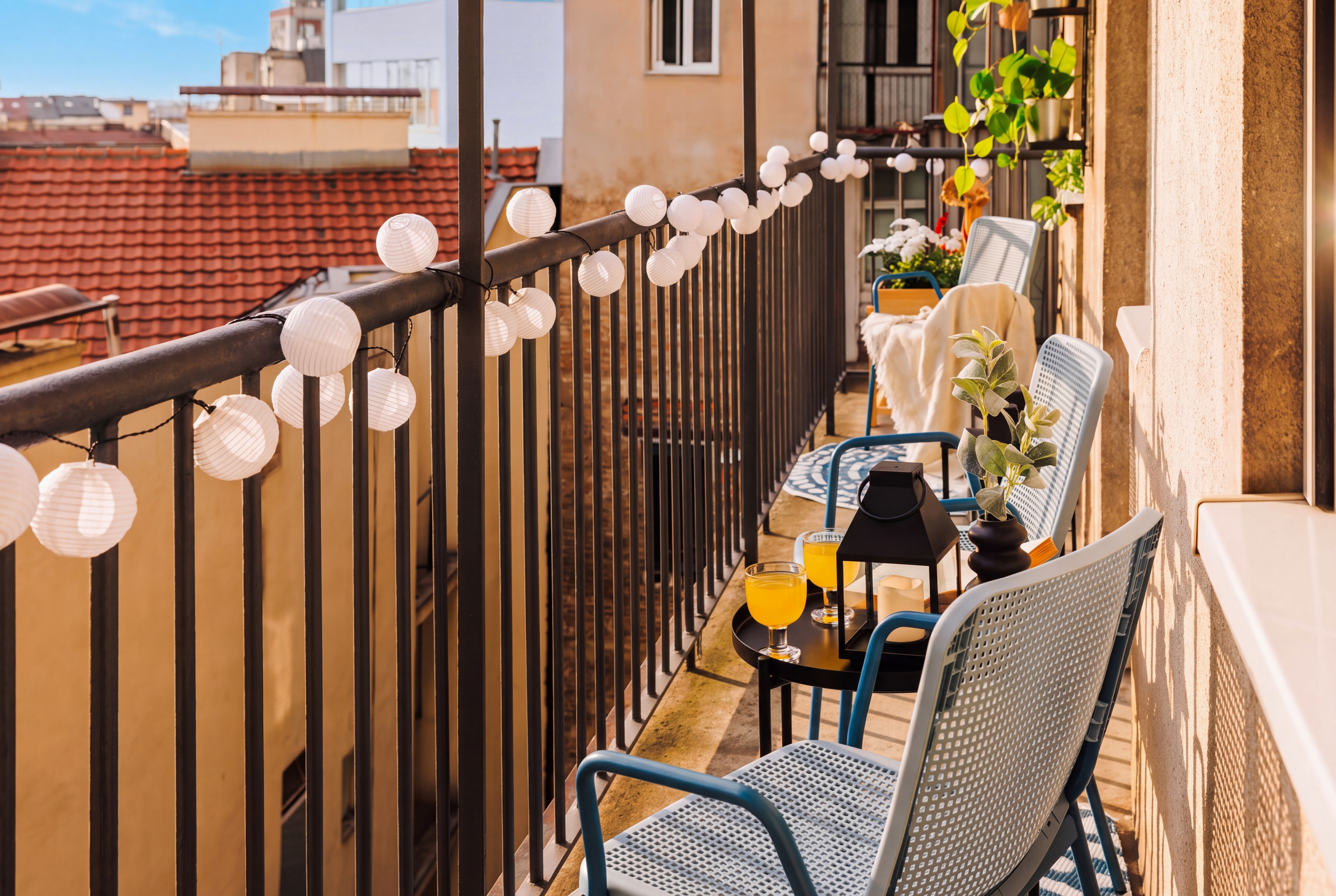 Sunny balcony with rooftop views, string lights, and cozy seating