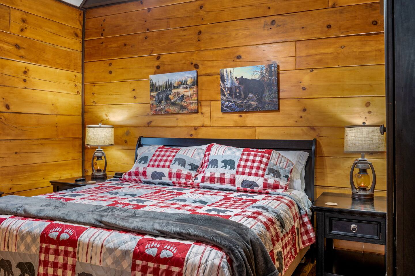 King bedroom with wood walls and a red plaid quilt
