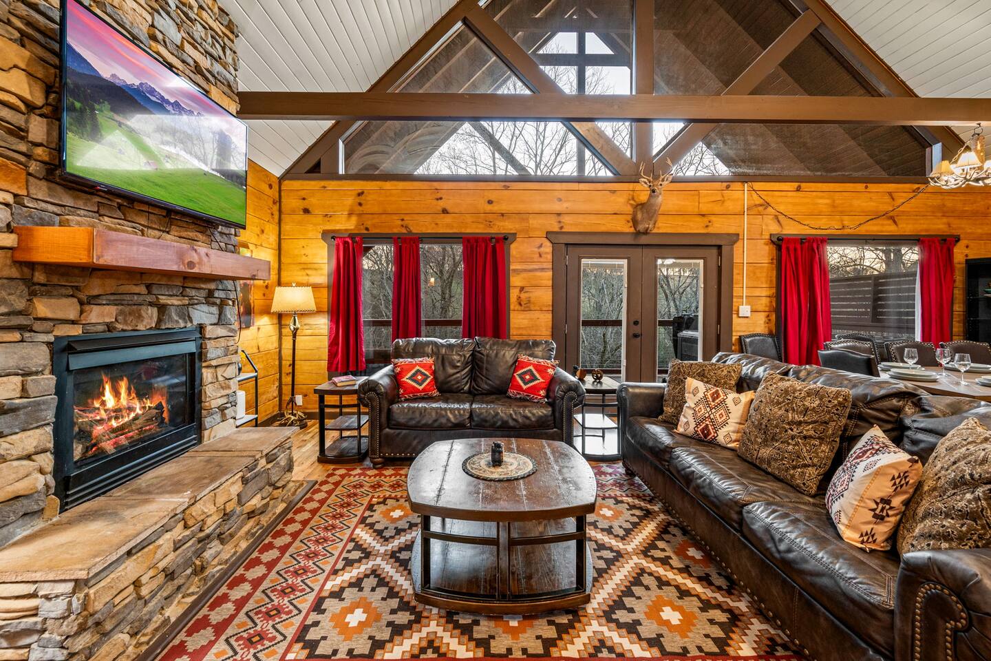 Great room with a stone fireplace, a TV, leather sofas and a vaulted ceiling