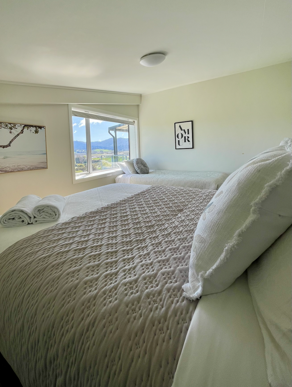 Bedroom 2 Bright twin bedroom with cozy linens and scenic mountain views 1 queen and 1 king single with a trundle