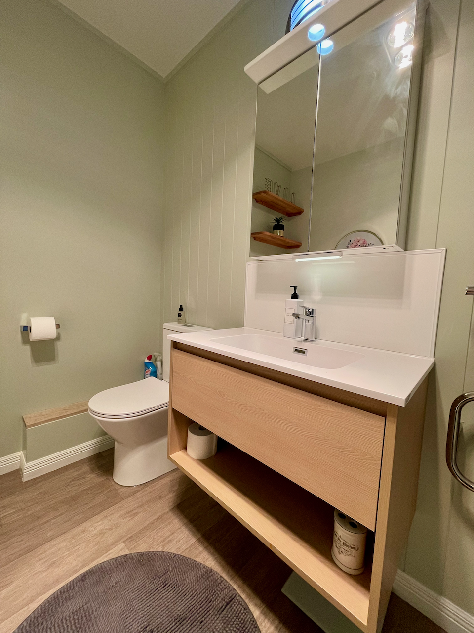 Bright modern bathroom with sleek vanity, mirror storage, and warm finishes