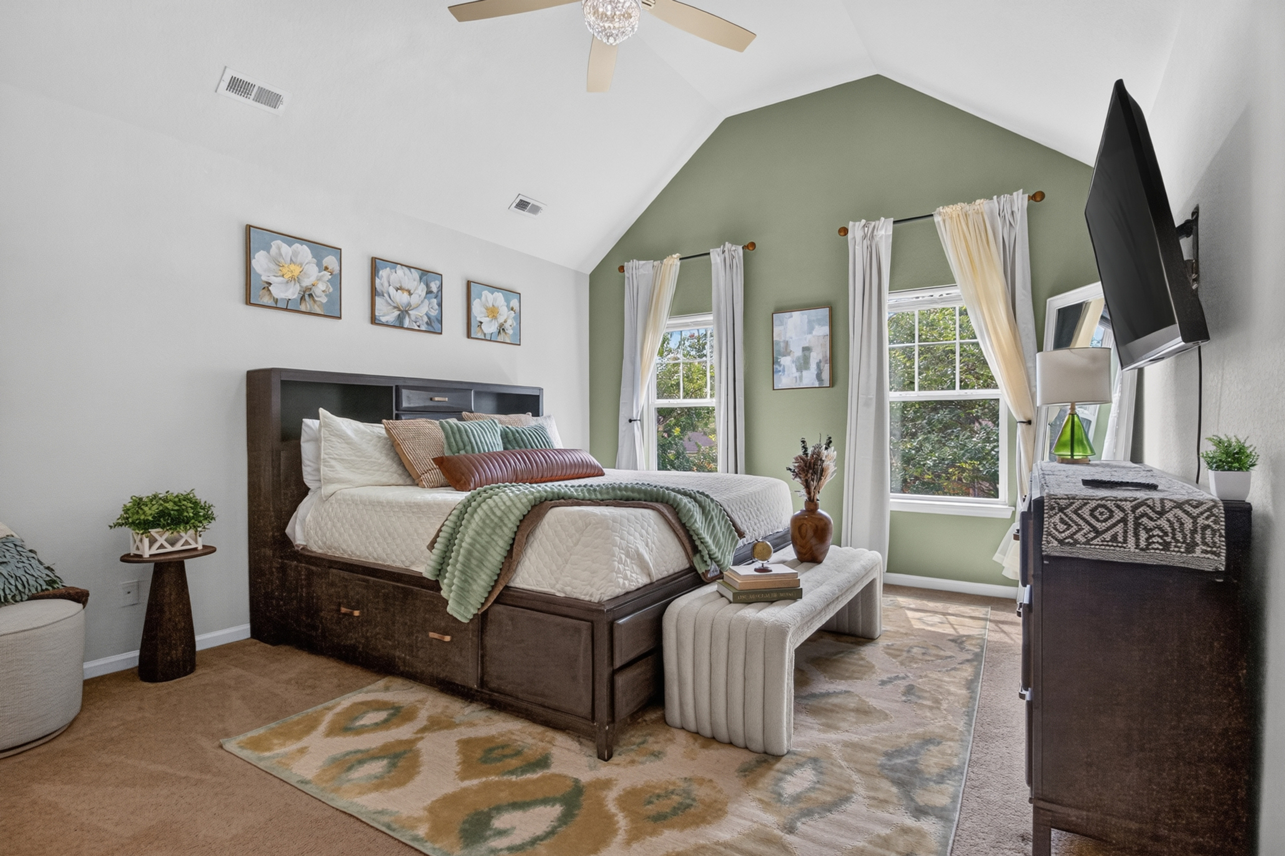 Bright vaulted bedroom with accent wall, storage bed, and TV