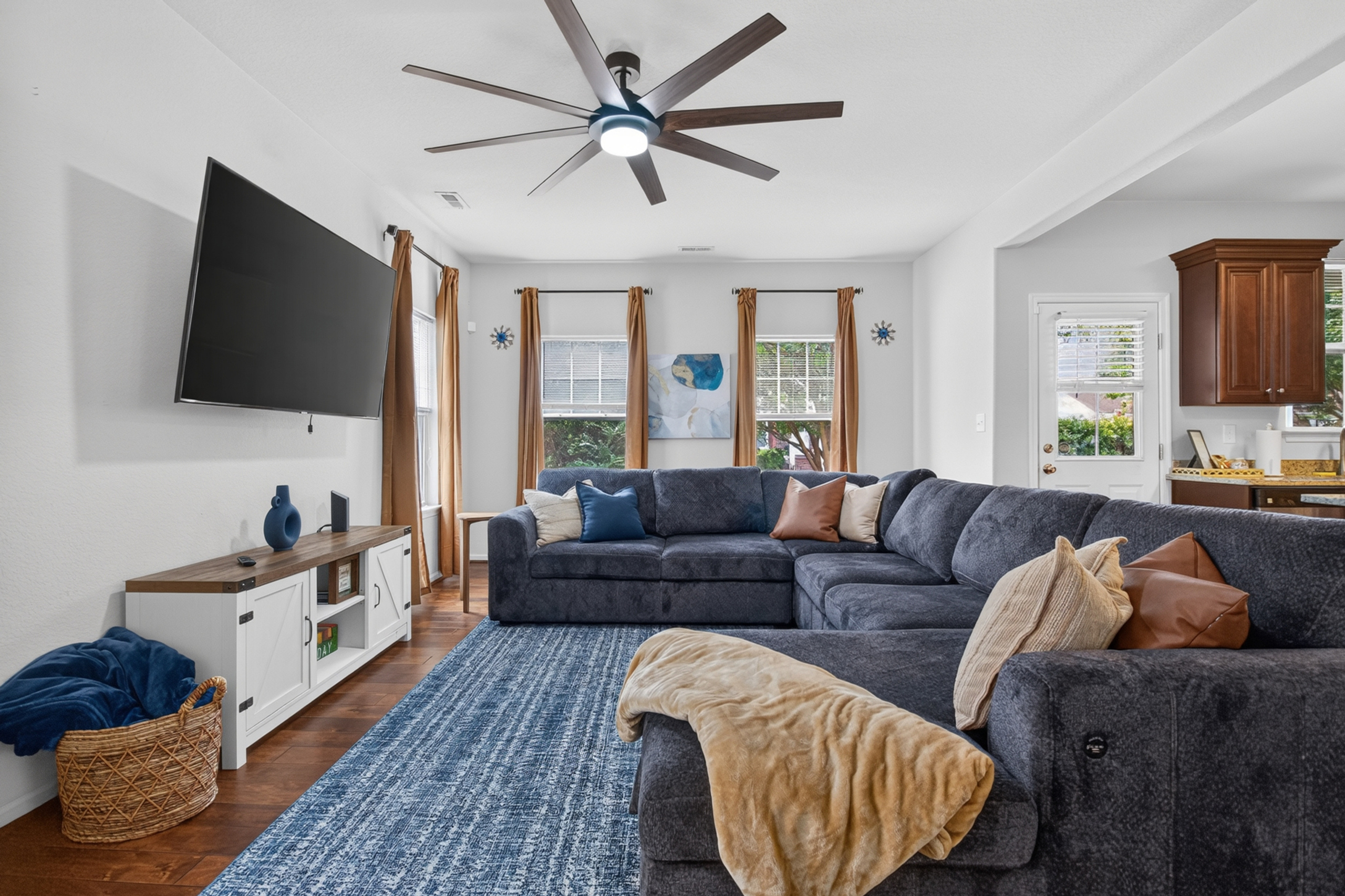 Spacious, sunlit living room with oversized sectional and big-screen TV