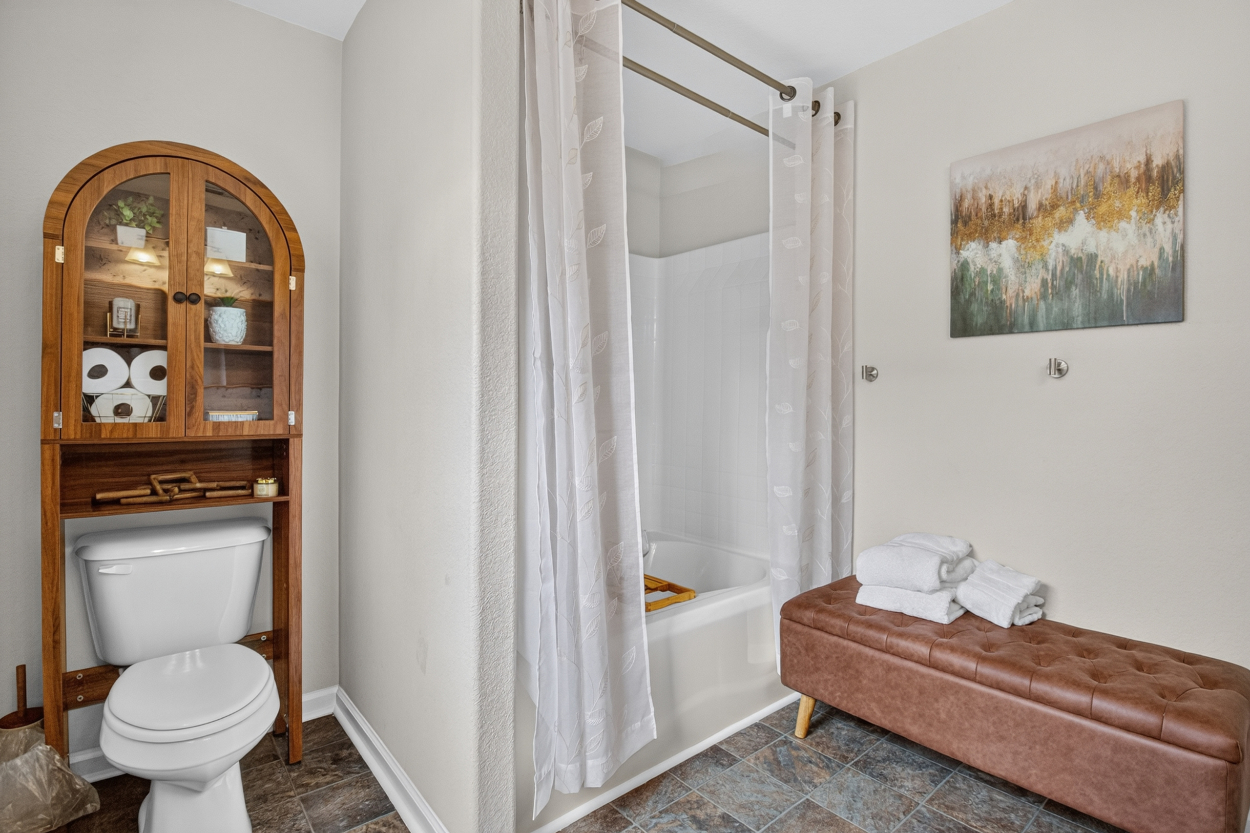 Bright bathroom with tub-shower, extra storage, and guest-ready touches