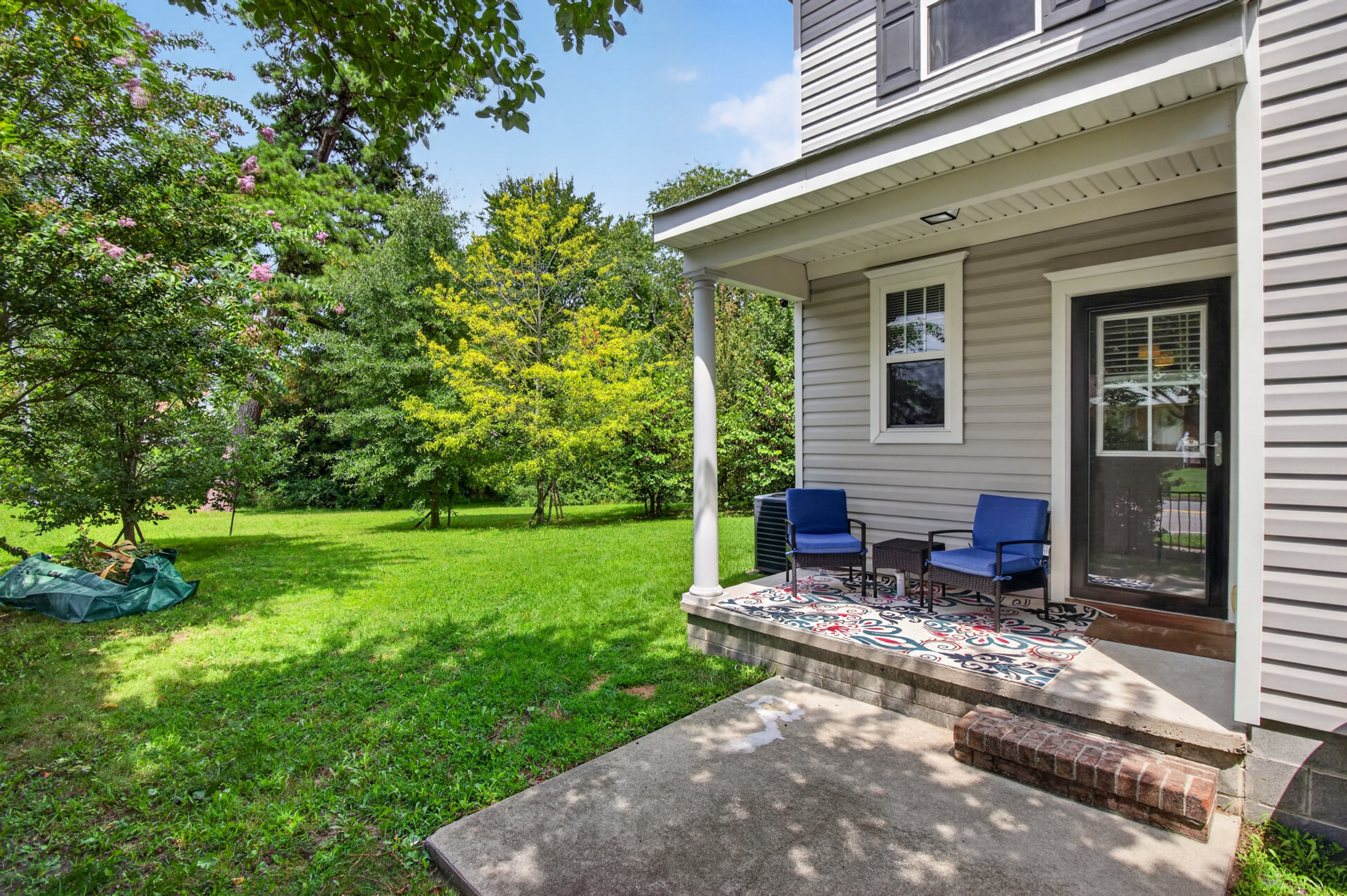 Charming covered porch with seating and a spacious, tree-lined yard