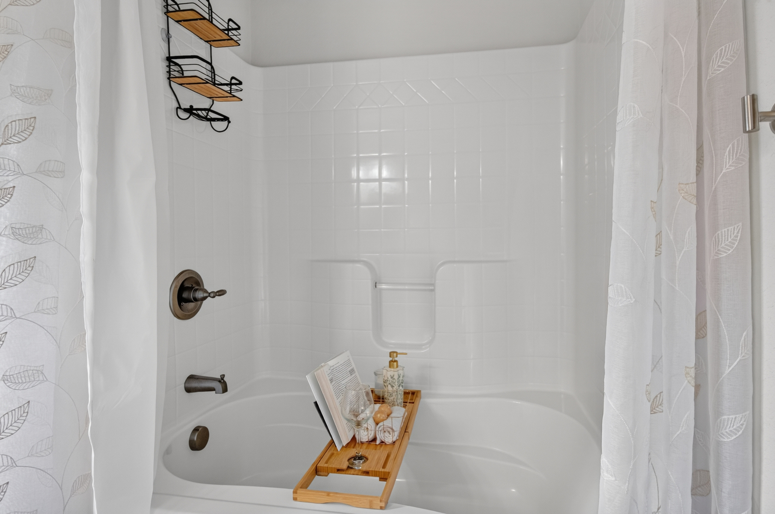 Bright spa-like tub with bath caddy and convenient shower storage