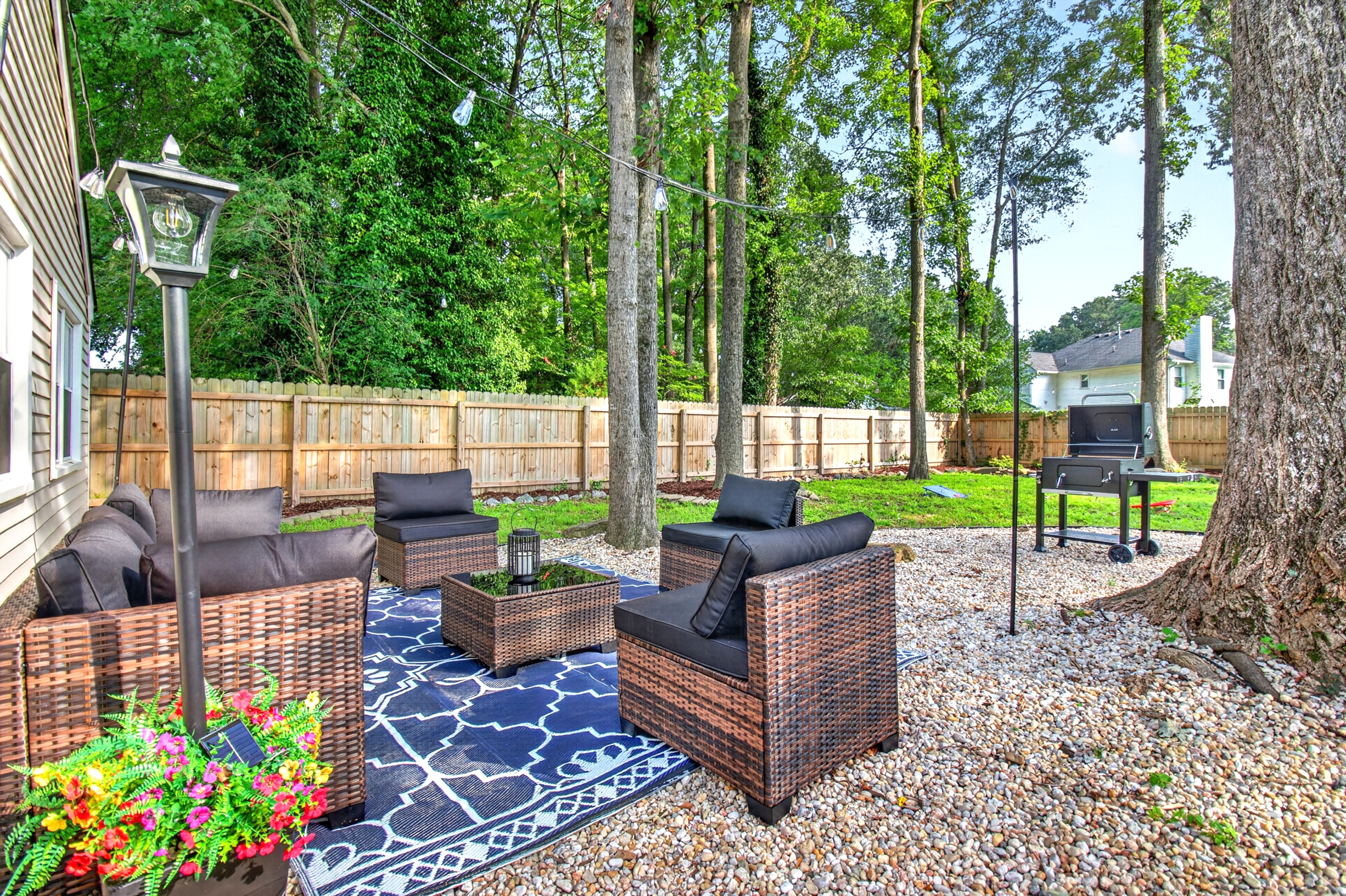 Private fenced backyard with cozy lounge seating, string lights & grill