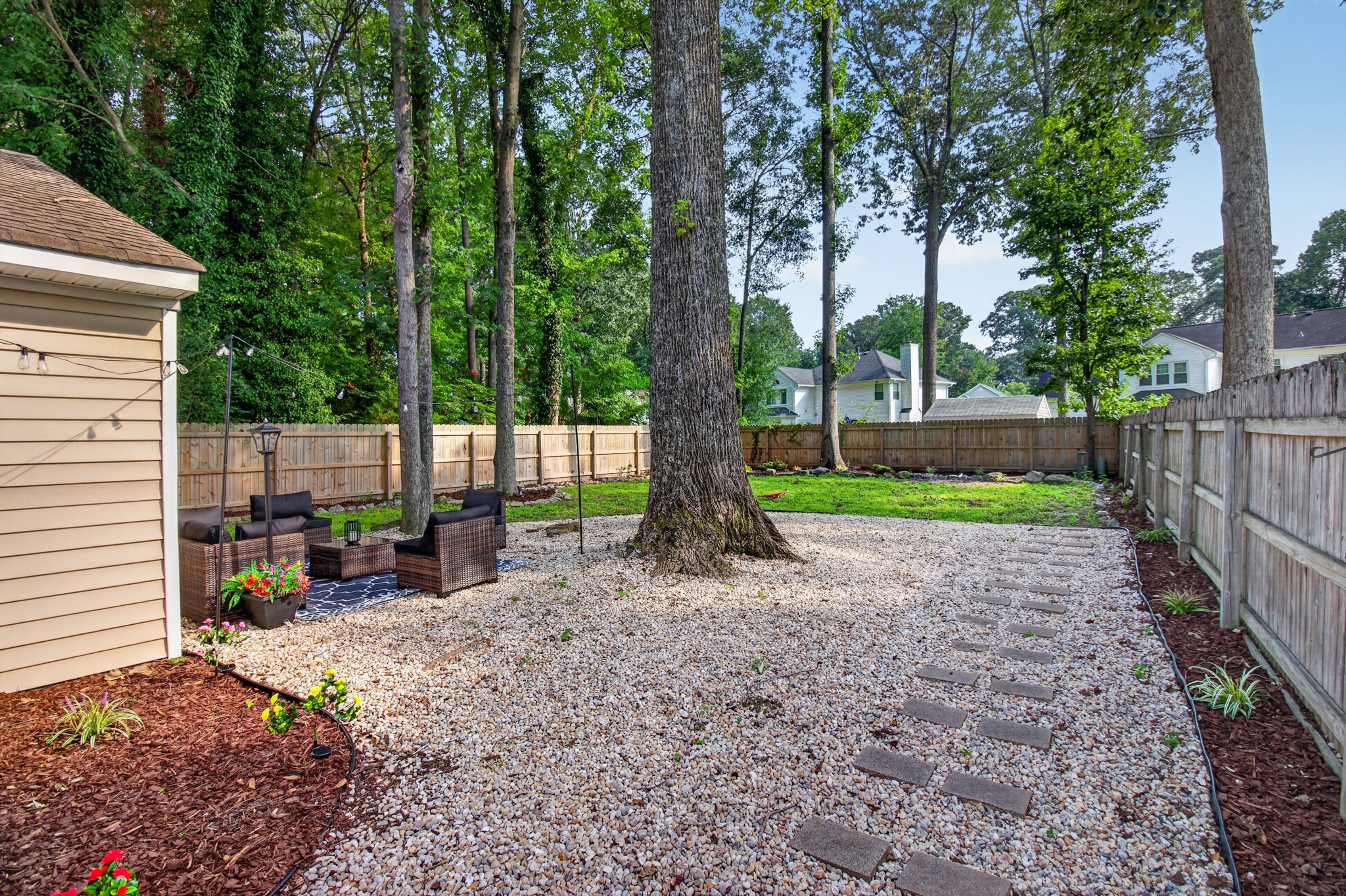 Private fenced backyard with patio seating and peaceful wooded views
