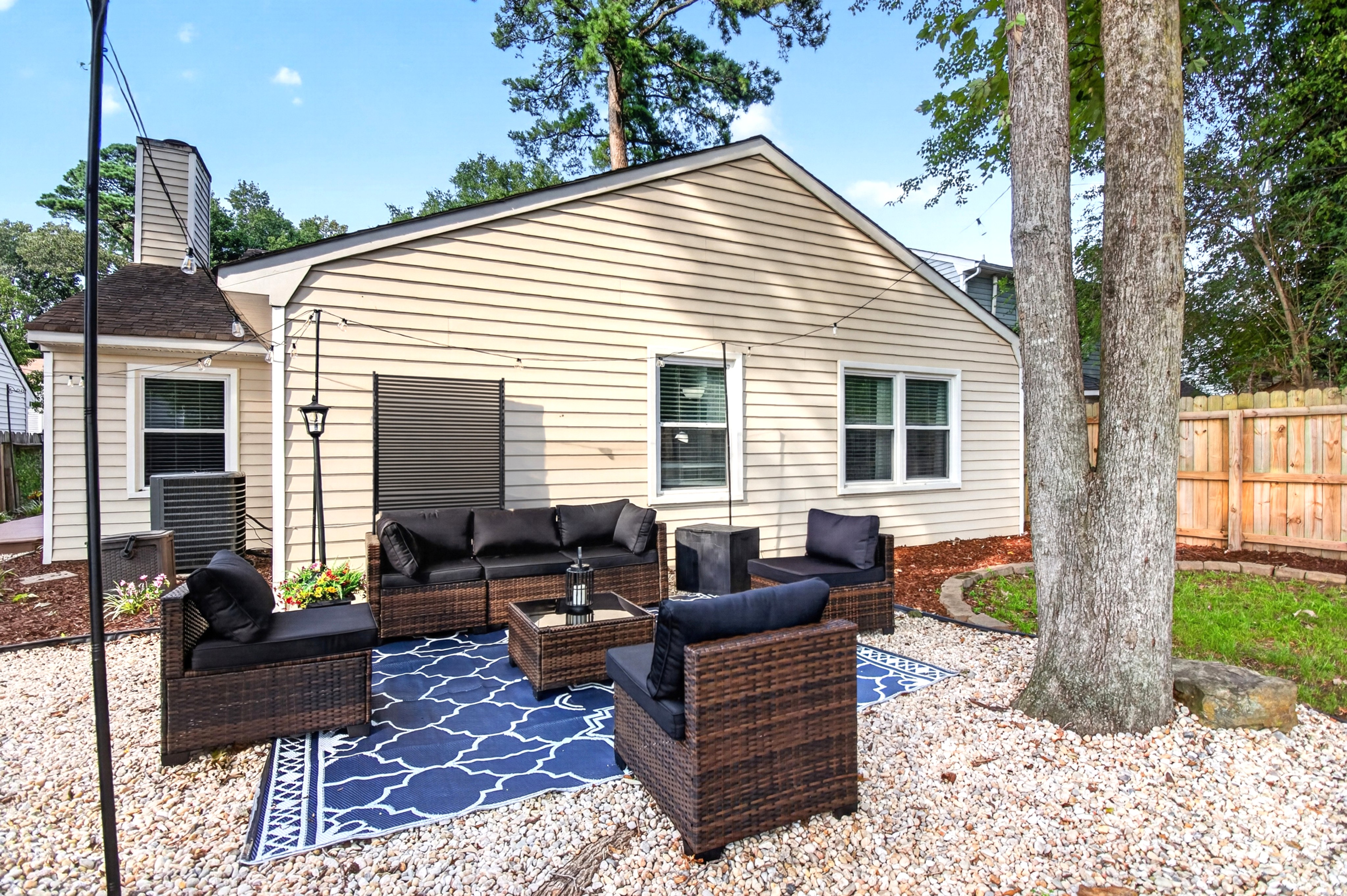 Private outdoor lounge with stylish seating, string lights, and shade trees