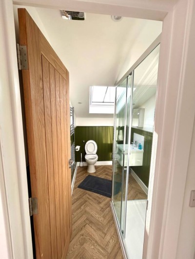 Modern bathroom in Greater London near Notting Hill, Acton, and Ealing! Features a clean toilet, wall-mounted sink, large mirror, heated towel rail, and stylish two-tone walls with wooden flooring.
