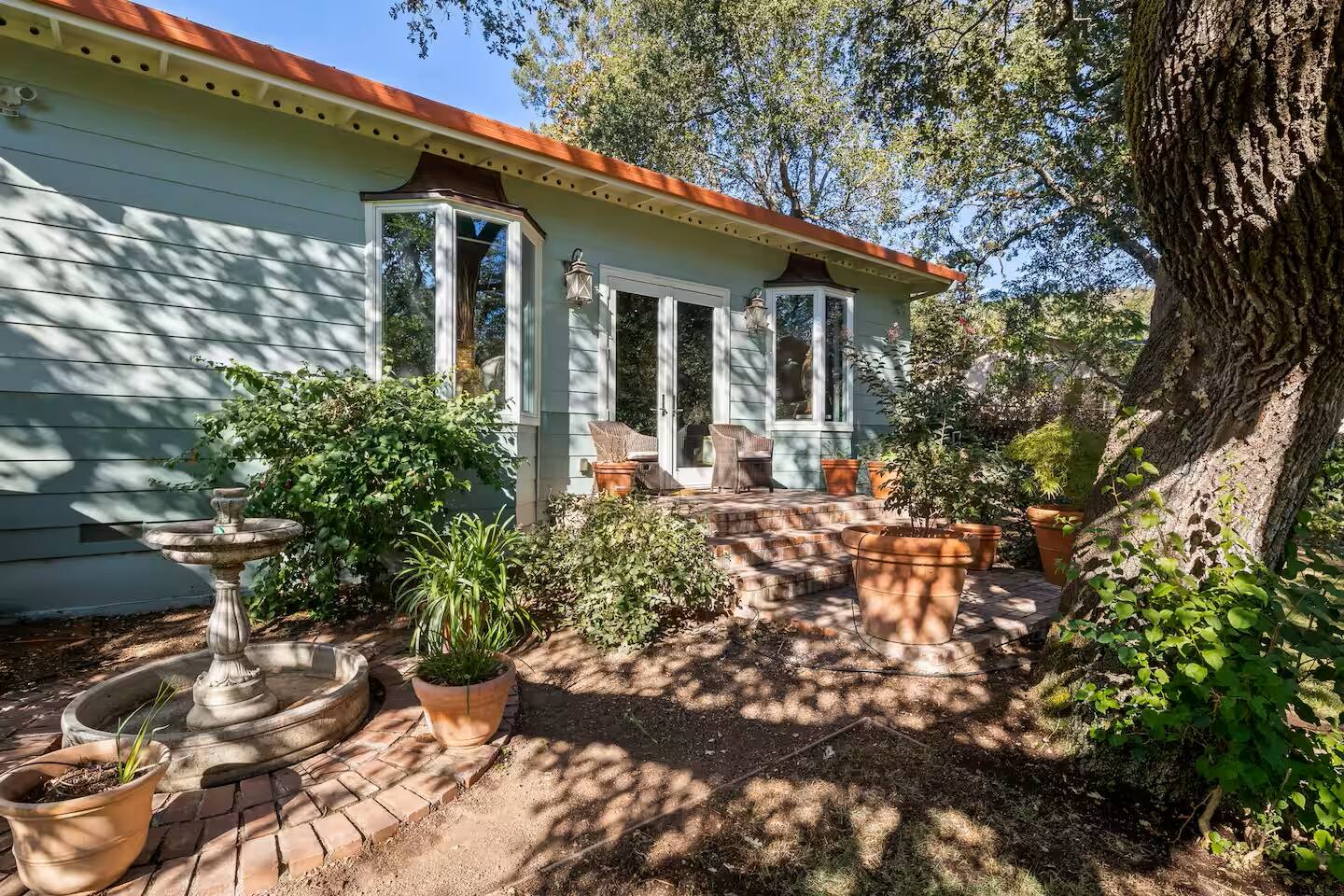 Serene outdoor retreat! Lush greenery and charming patio seating make for the perfect relaxation spot.