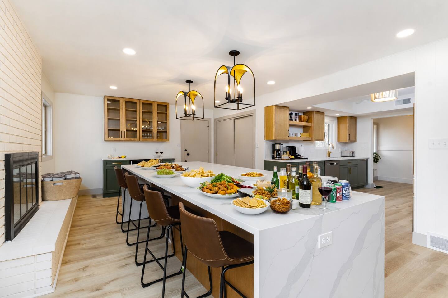 Open kitchen with a long white island, bar stools and pendant lights