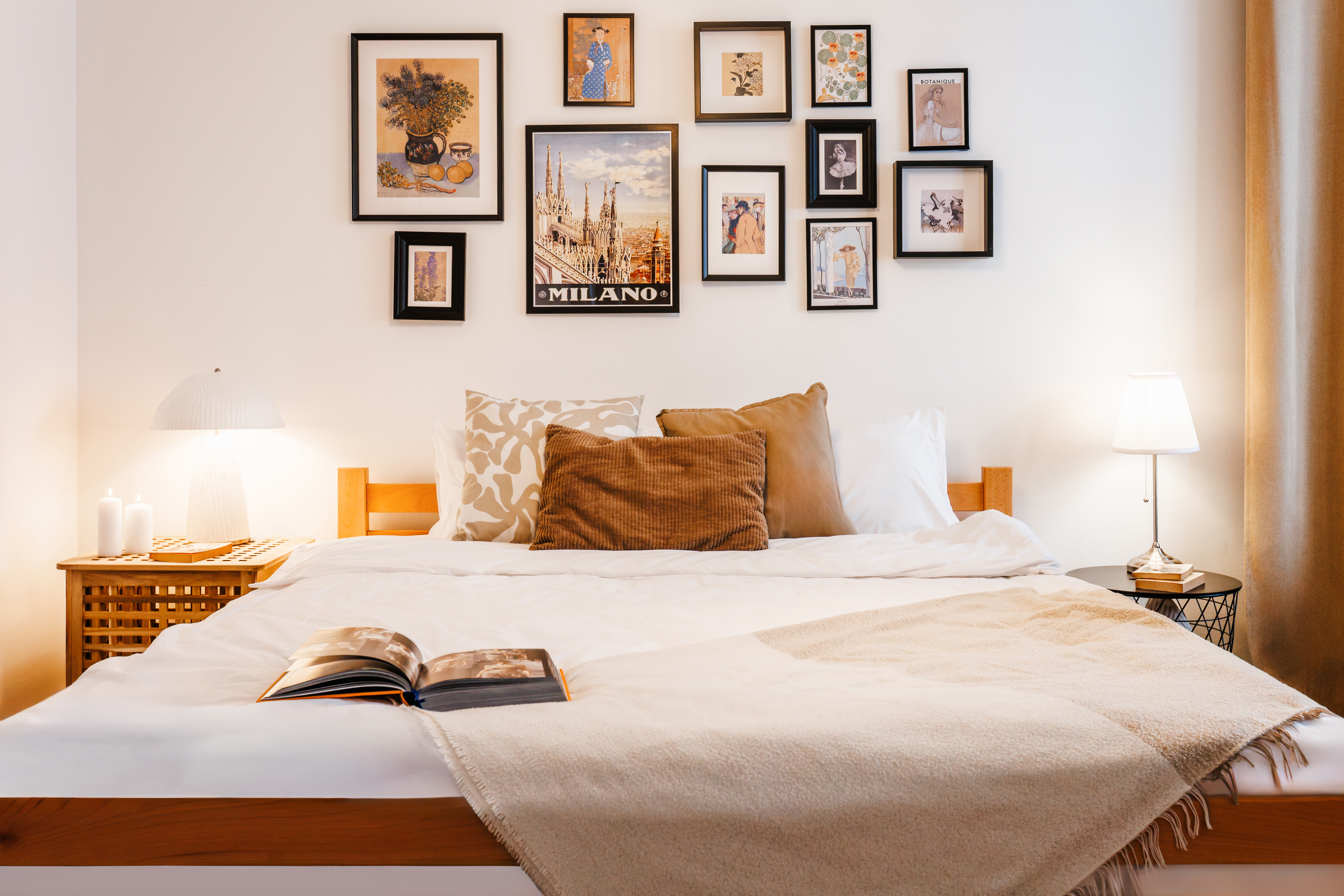 Cozy, art-filled bedroom with warm lighting and inviting layered bedding