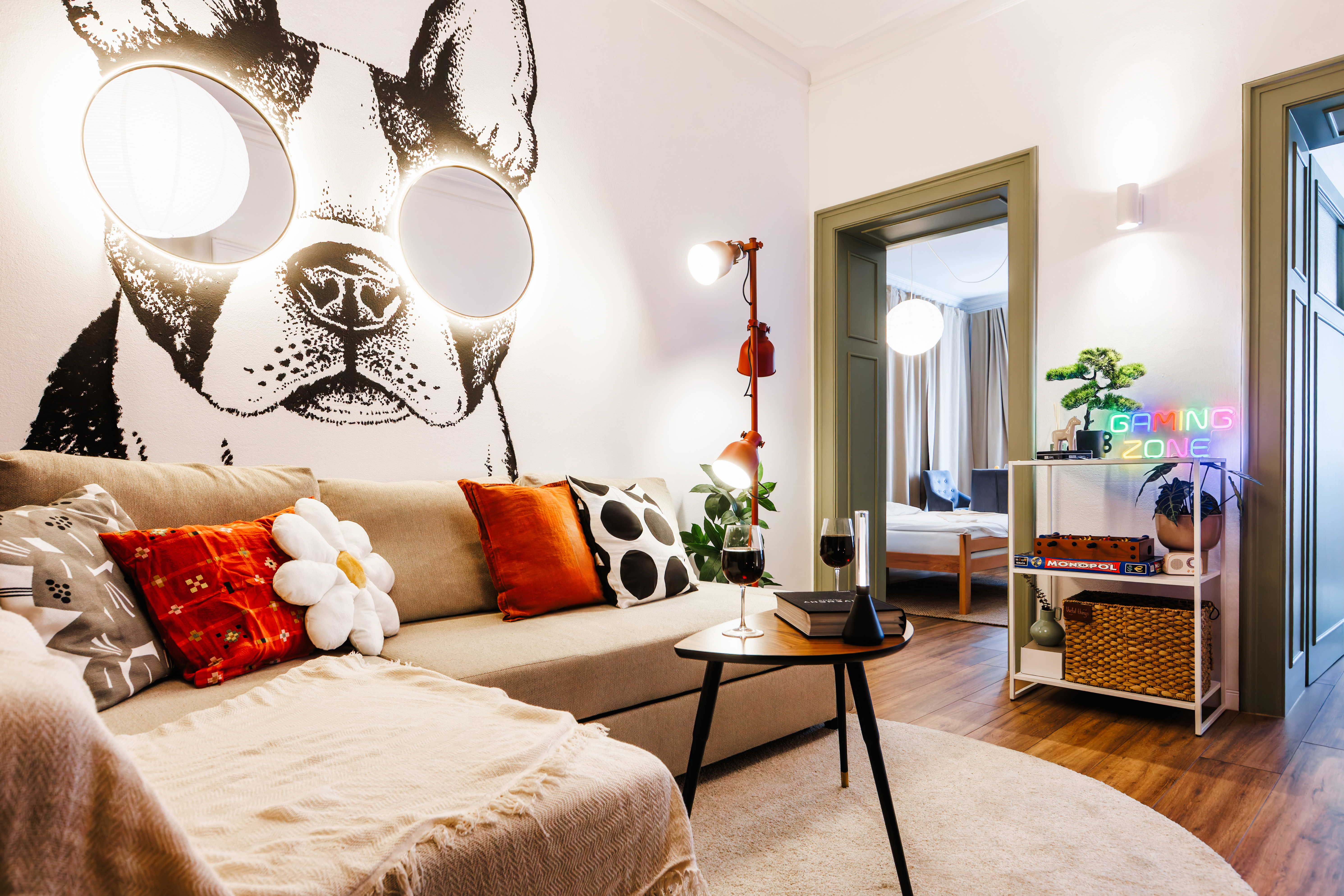 Playful designer lounge with cozy seating, bold mural, and gaming nook