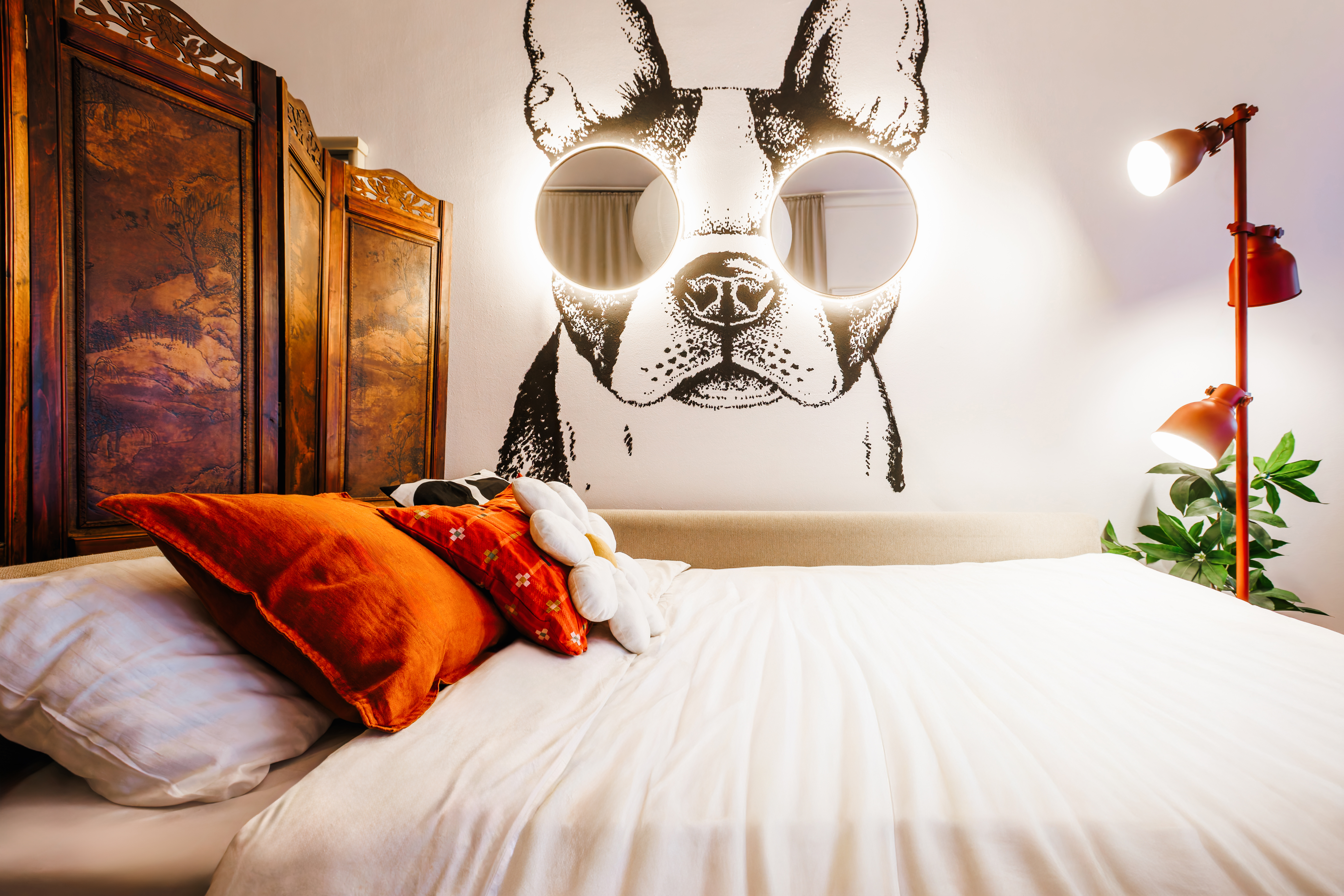 Stylish bedroom with bold dog mural, warm lighting, and cozy plush bedding