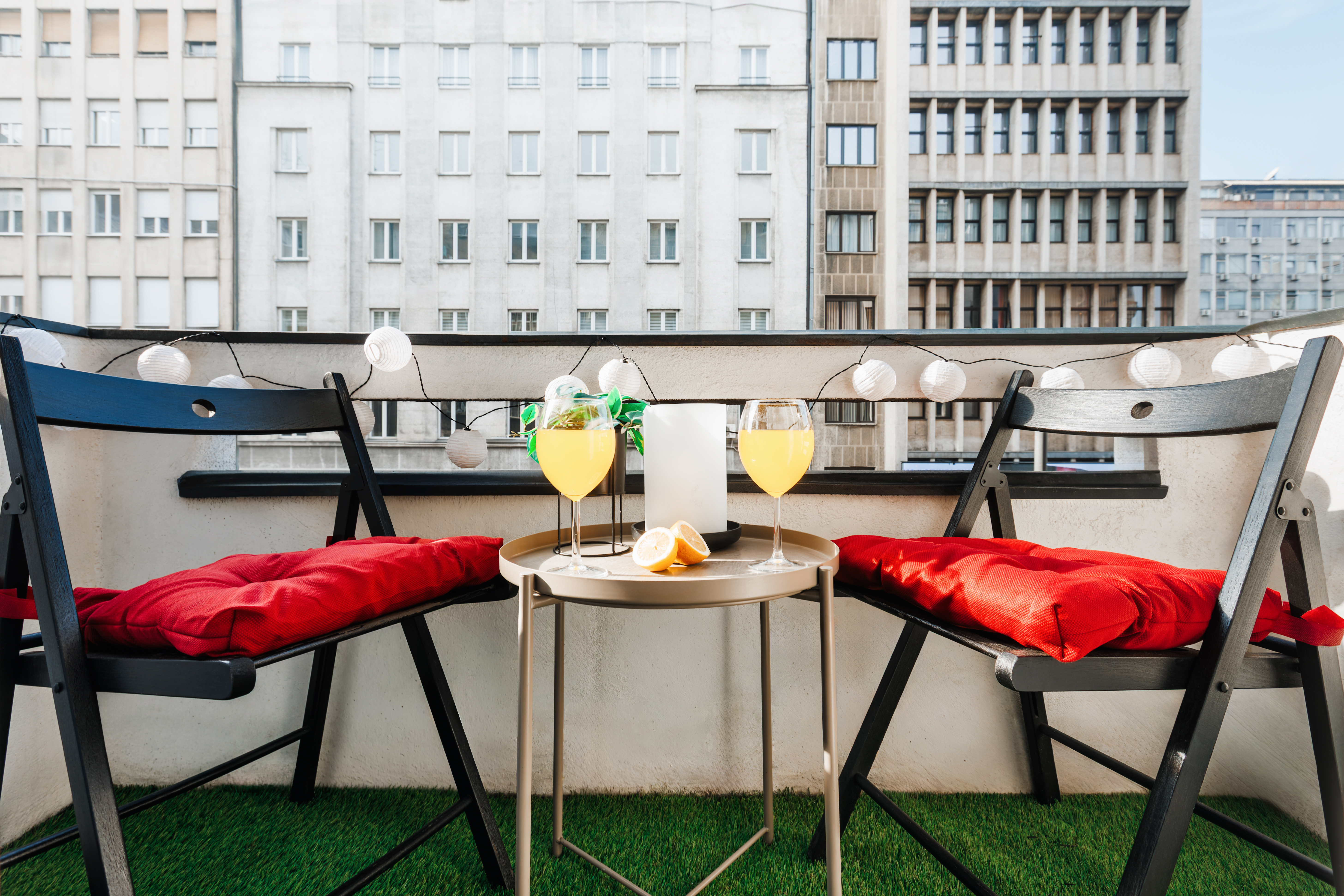 Cozy city-view balcony with string lights and seating for two