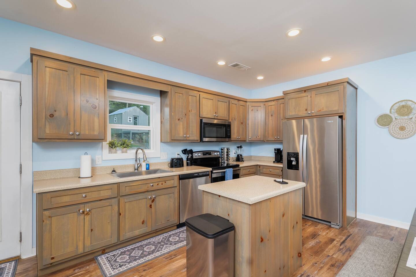 Fully stocked kitchen with cookware, cups, knives, coffee makers, and wine glasses