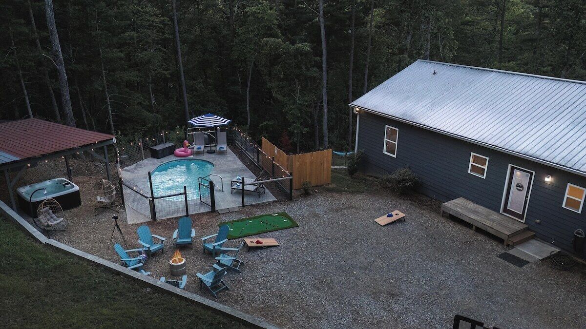 Backyard with cornhole, basketball hoop, pool, and hot tub