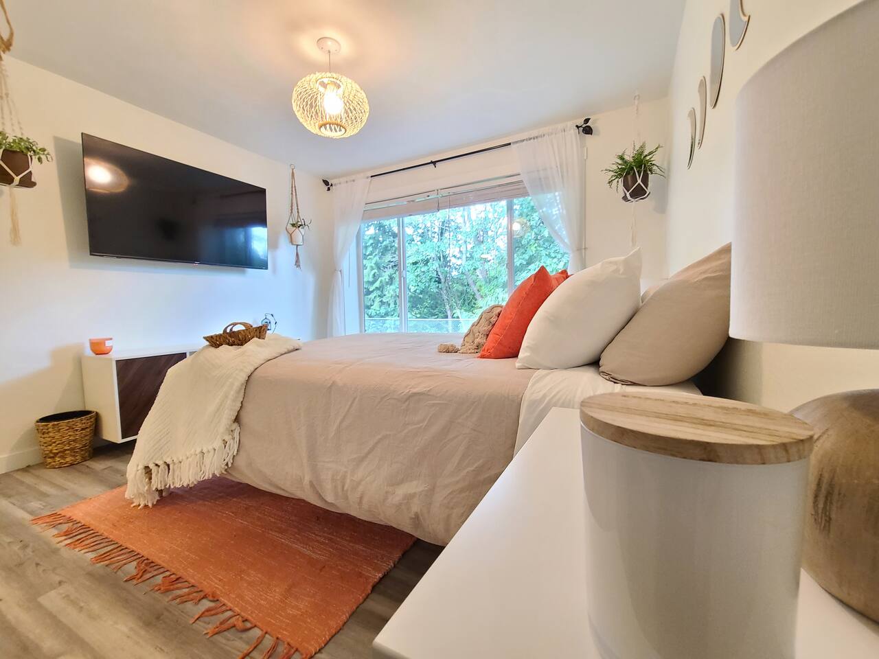 Unwind in this serene bedroom featuring a plush Lull queen mattress, a 55” TV for your entertainment, and a picturesque view through large windows that bring nature right into your room. The perfect retreat for rest and relaxation.