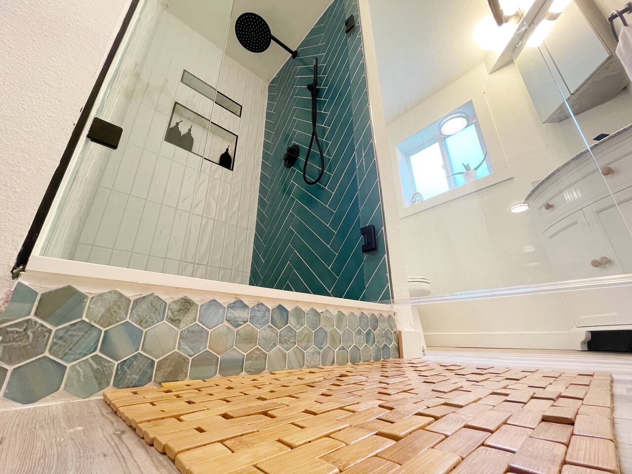Modern bathroom with a chic walk-in shower, herringbone tiles, and natural wood accents.