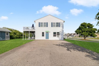 Side view of house with large driveway, backyard, shed, elevated deck and fire pit.