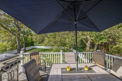 Elevated deck with seating and Propane Grill over looking backyard.