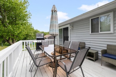 Deck off kitchen with table, chairs and outdoor grill. Access to back yard.