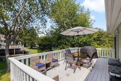 Deck off kitchen with table, chairs and outdoor grill. Access to back yard.