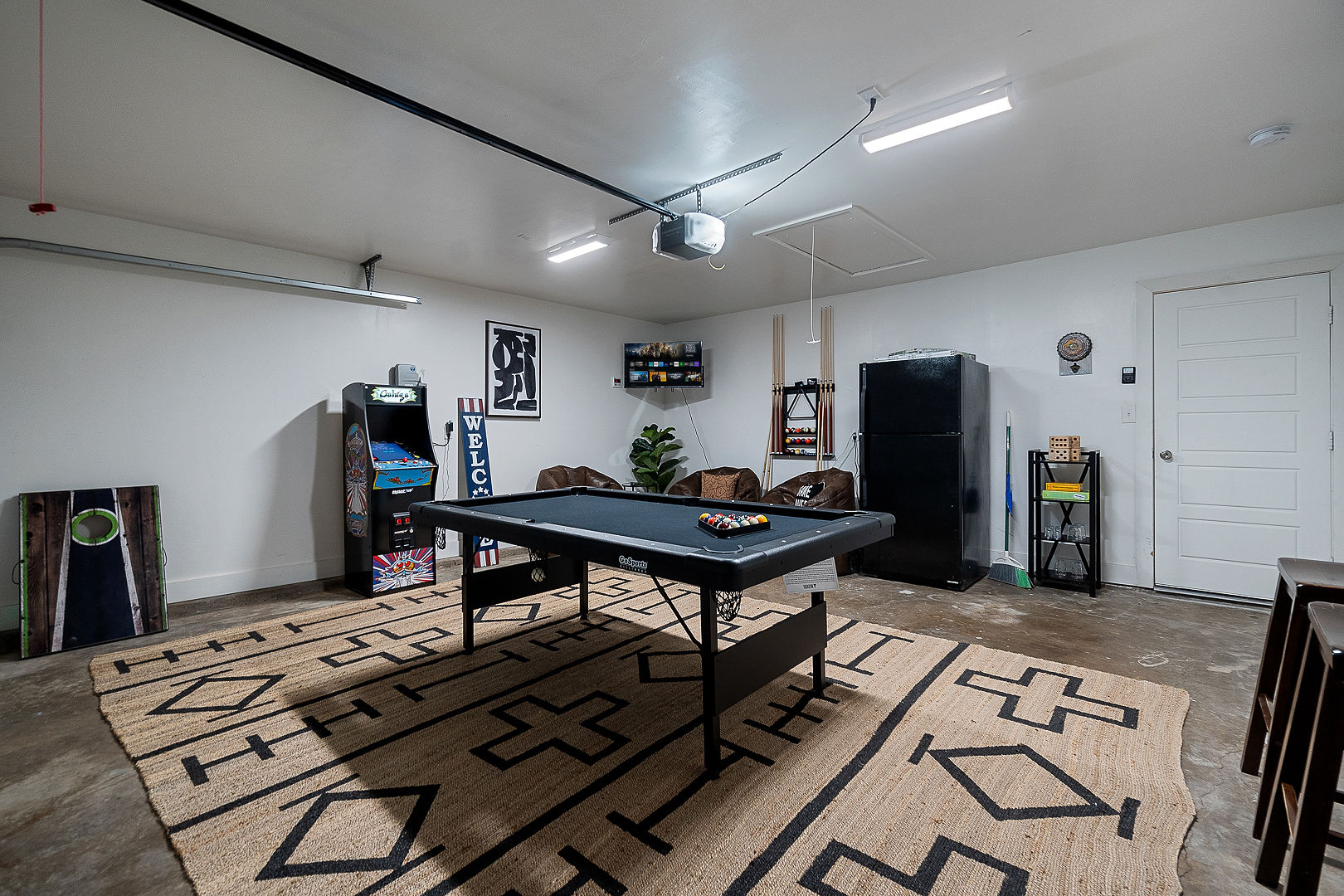 Spacious game room with pool table, arcade machine, TV, and lounge seating