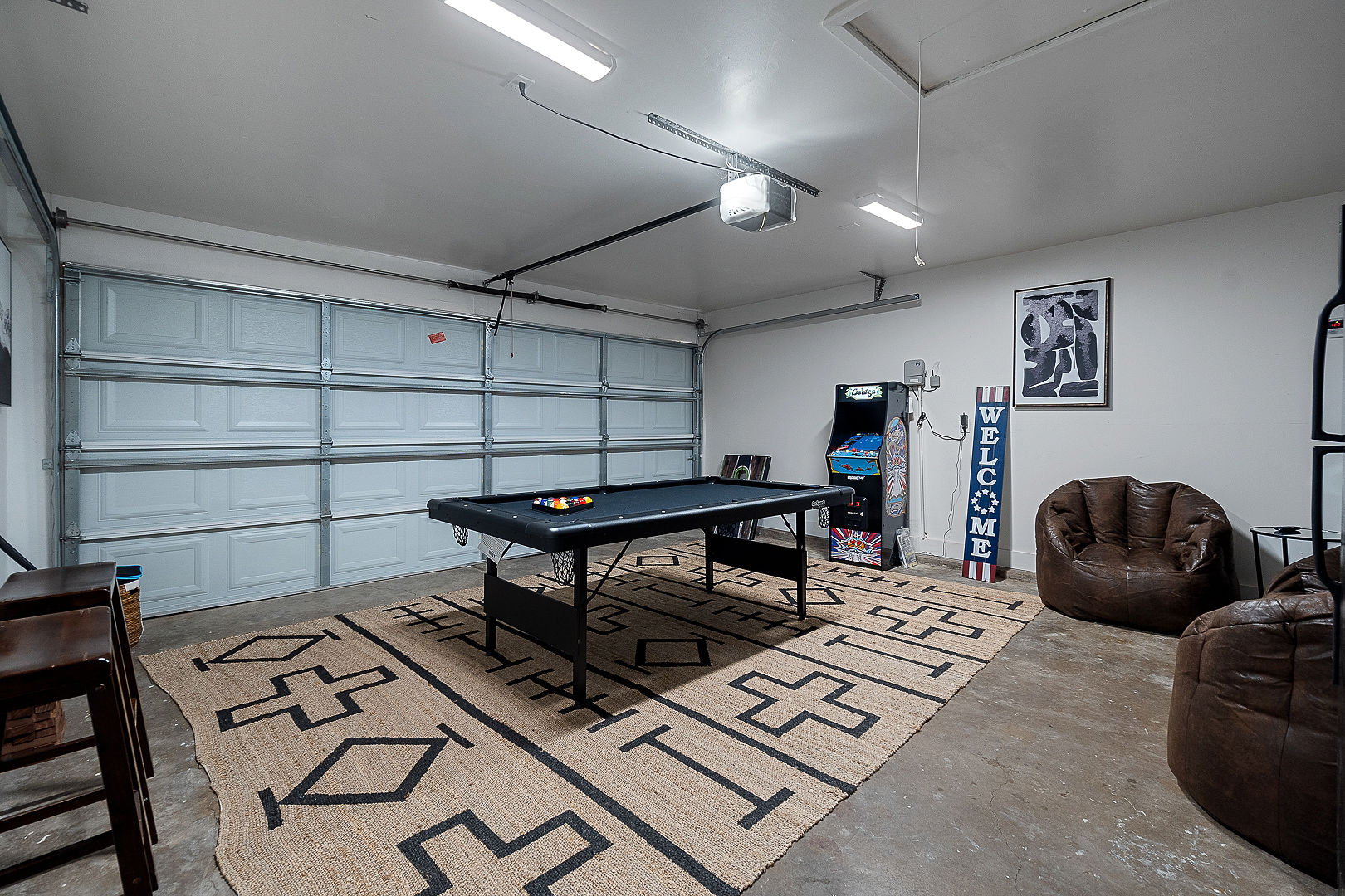 Garage game room with pool table, arcade machine, and lounge seating