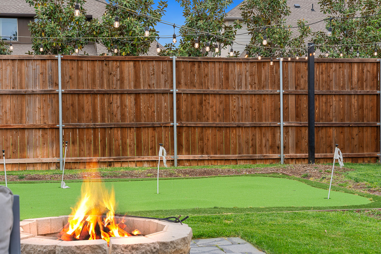 Private backyard with putting green, fire pit, and cozy string lights