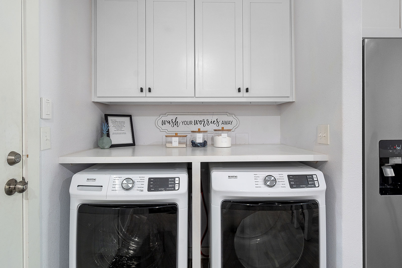 Bright modern laundry nook with full-size washer, dryer, and storage