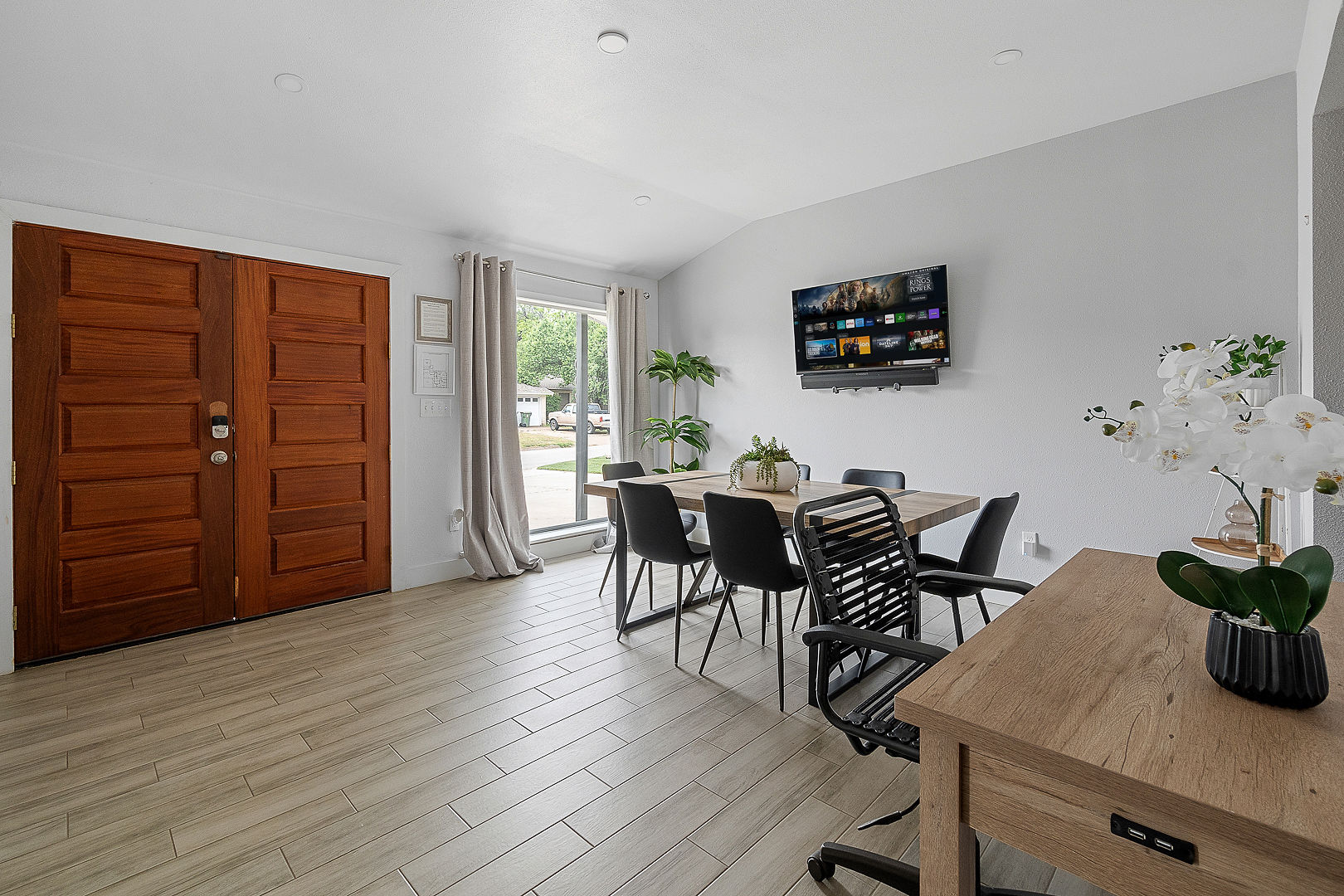 Bright modern dining area with workspace, TV, and natural light