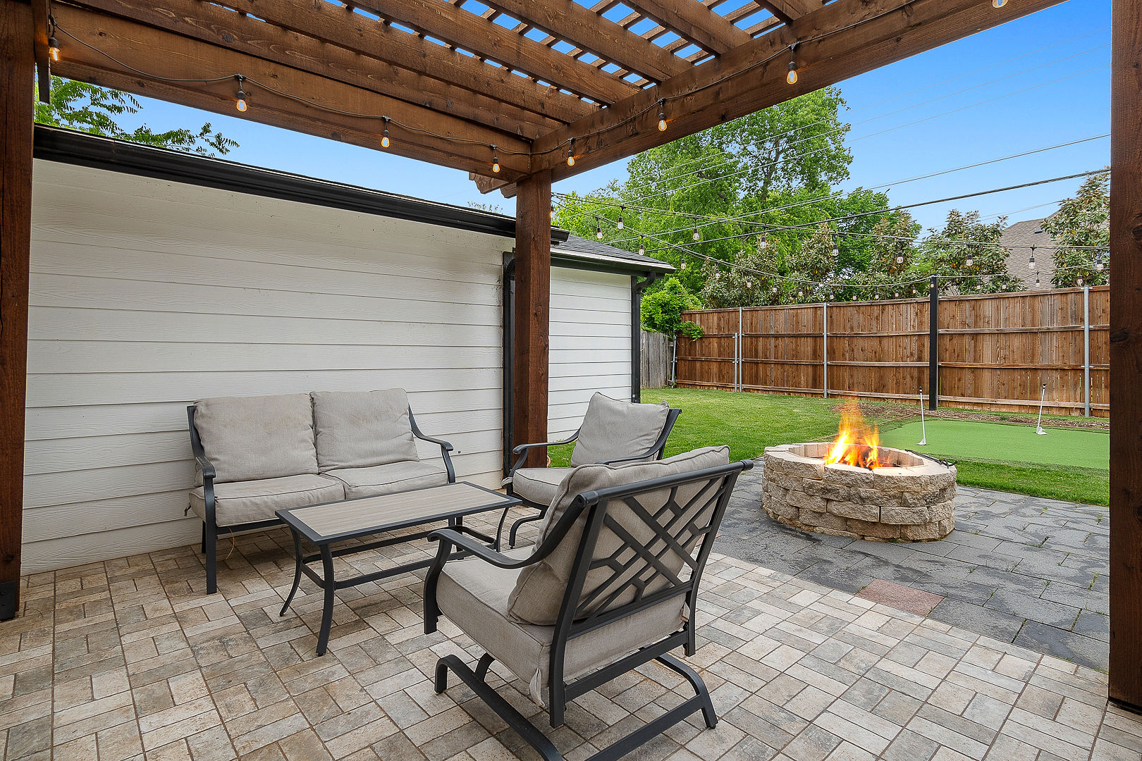 Cozy covered patio with string lights, lounge seating, and fire pit