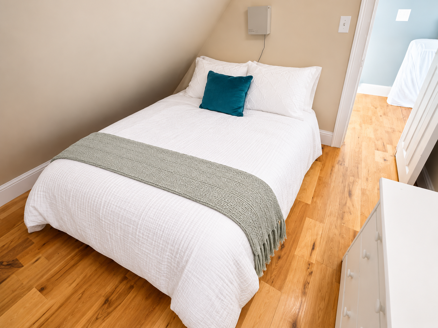 Cozy minimalist bedroom with warm wood floors and crisp white bedding