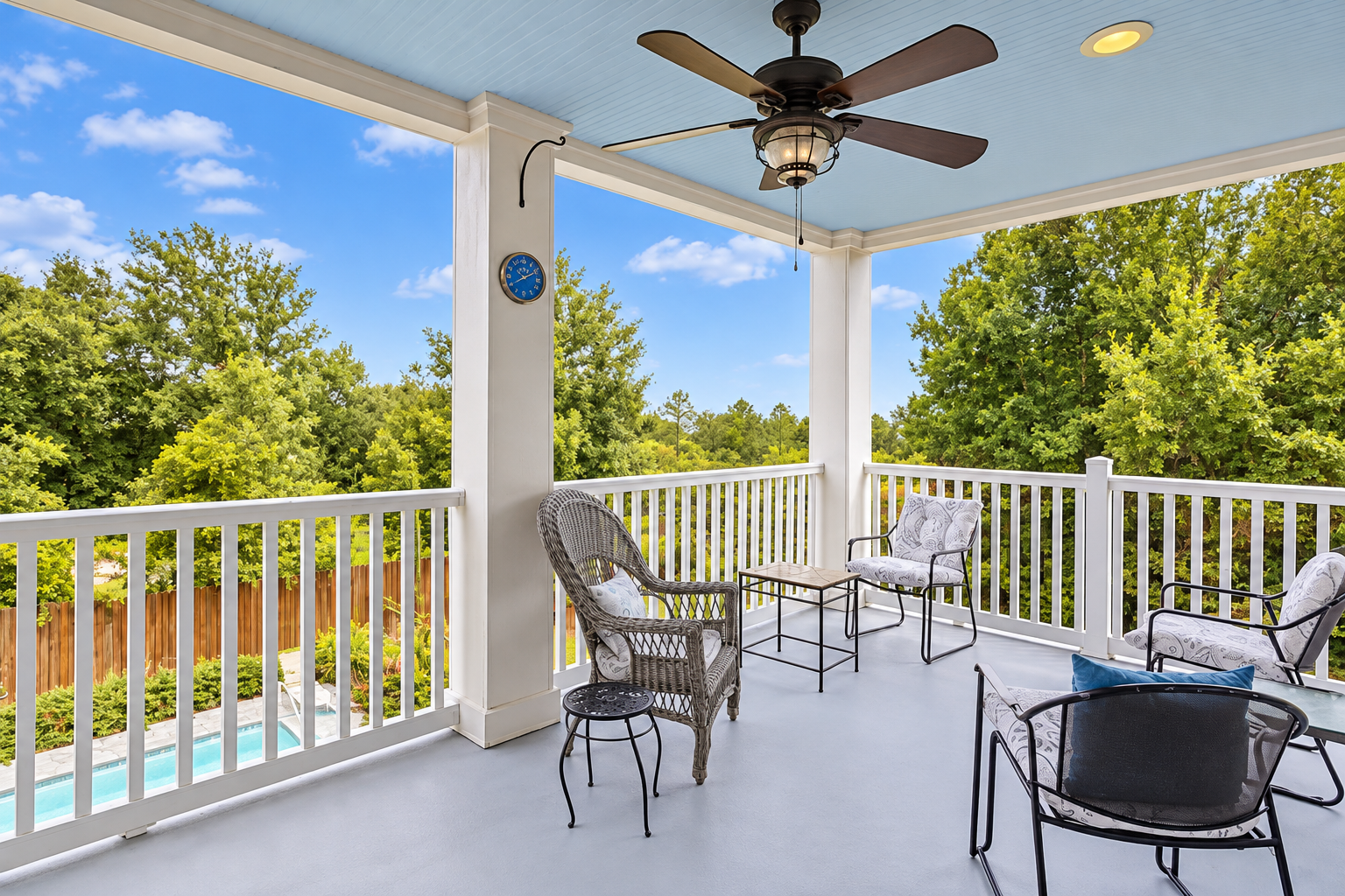 Covered balcony with comfy seating, ceiling fan, and pool views