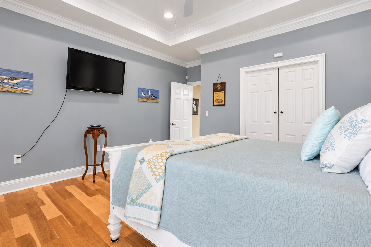 Spacious, serene bedroom with hardwood floors and wall-mounted TV