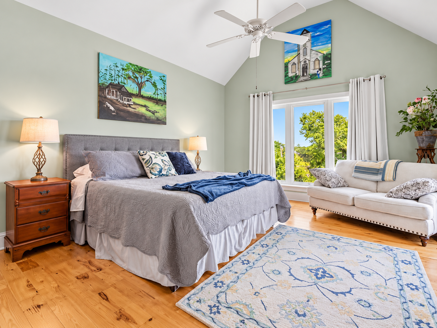 Bright king bedroom with vaulted ceilings, large windows, and cozy sitting area