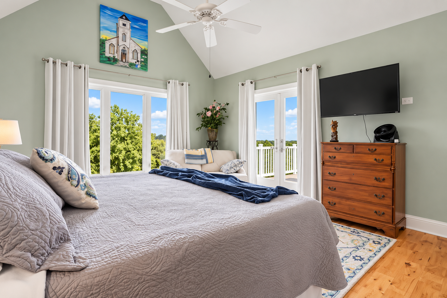 Bright vaulted bedroom with balcony access and peaceful scenic views