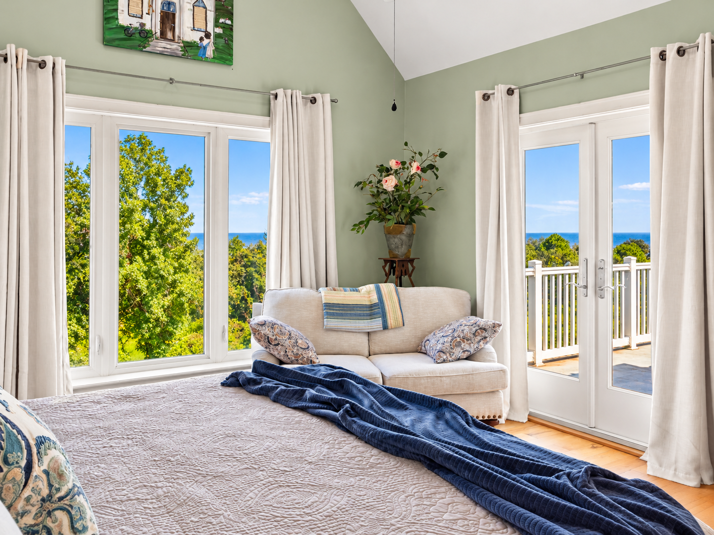 Bright bedroom with water views, cozy seating, and private balcony access