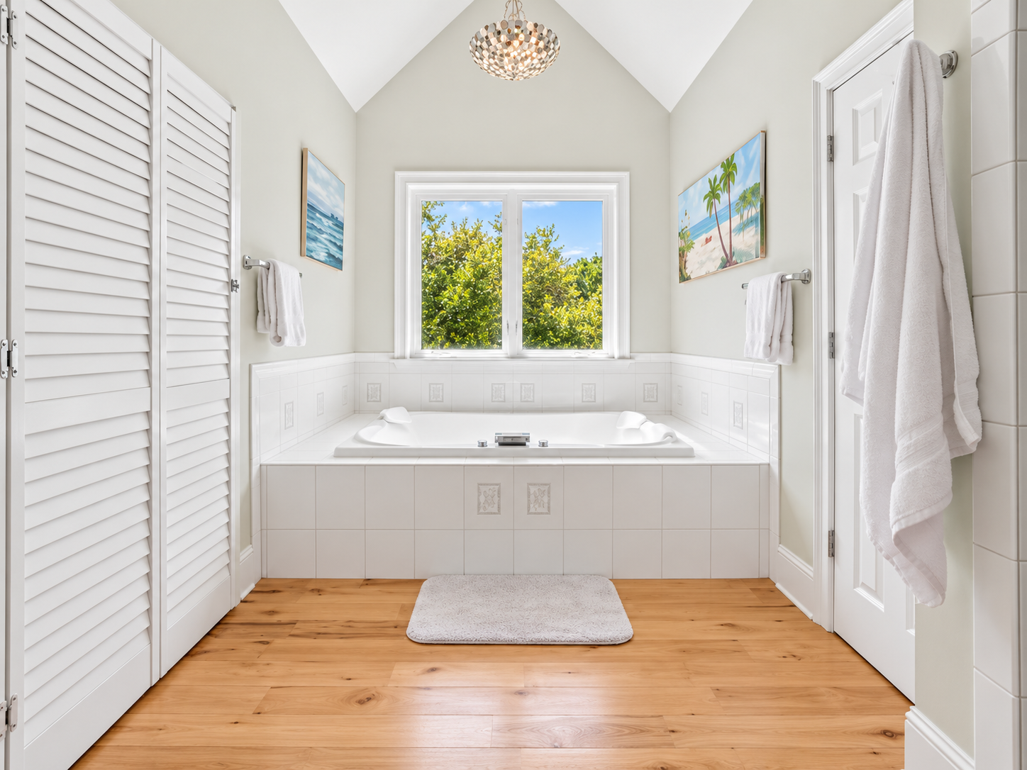 Bright spa-style bath with soaking tub, vaulted ceiling, and garden views