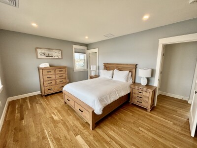 Bright, spacious bedroom with hardwood floors and stylish wood furnishings