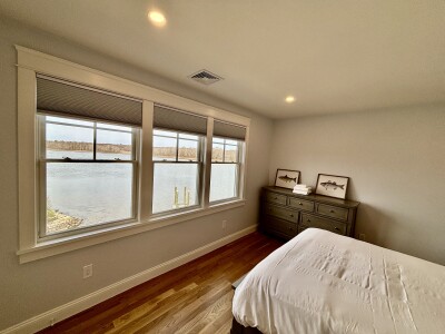 Peaceful waterfront bedroom with hardwood floors and stunning lake views